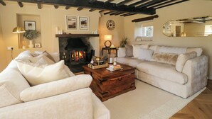 A cozy living room with a fireplace, two sofas, a coffee table, and a mirror. - Barn Howe (Kendal)