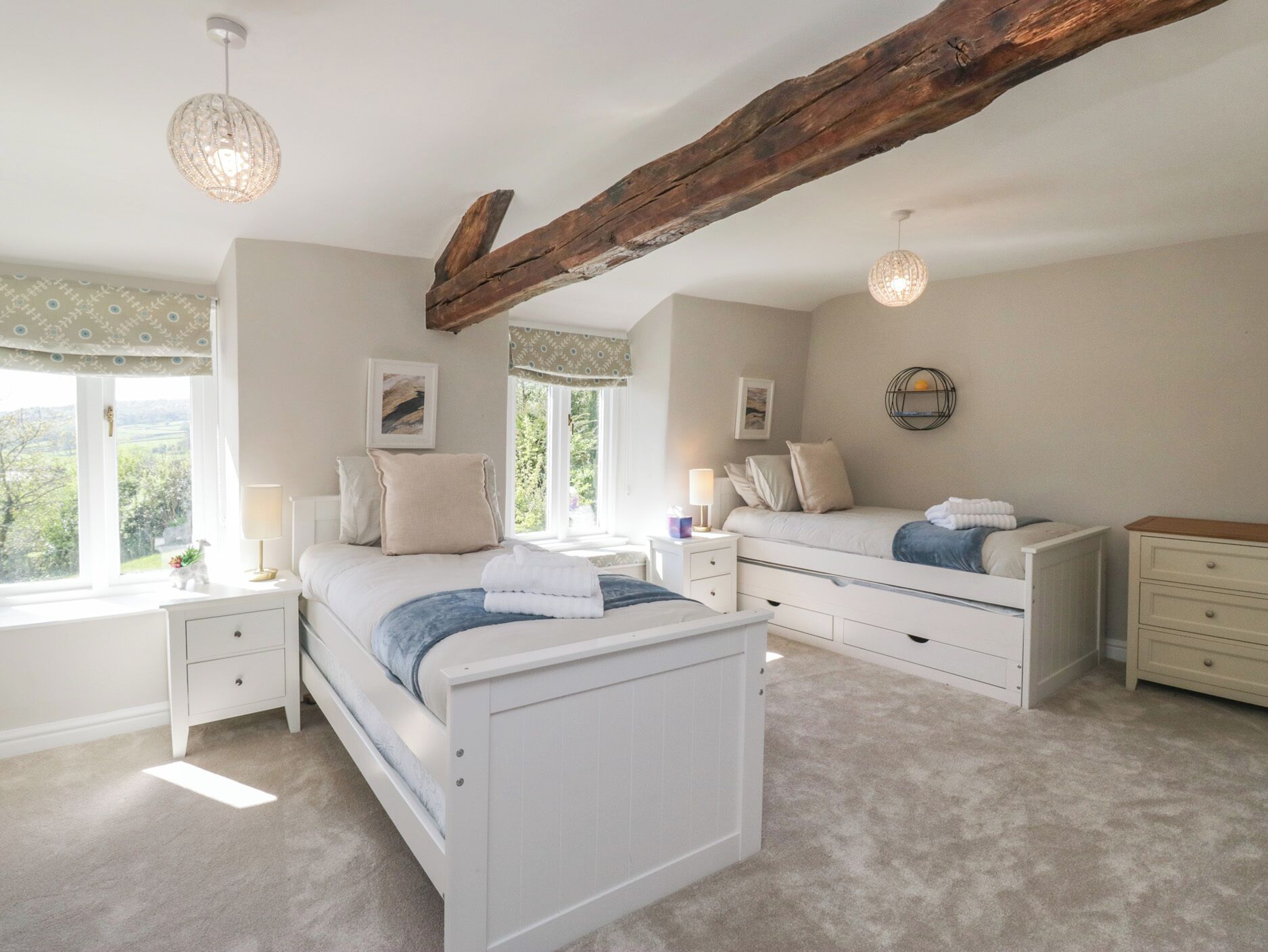 A bedroom with a large bed, bedside tables, a window with curtains, and a wooden ceiling beam.
