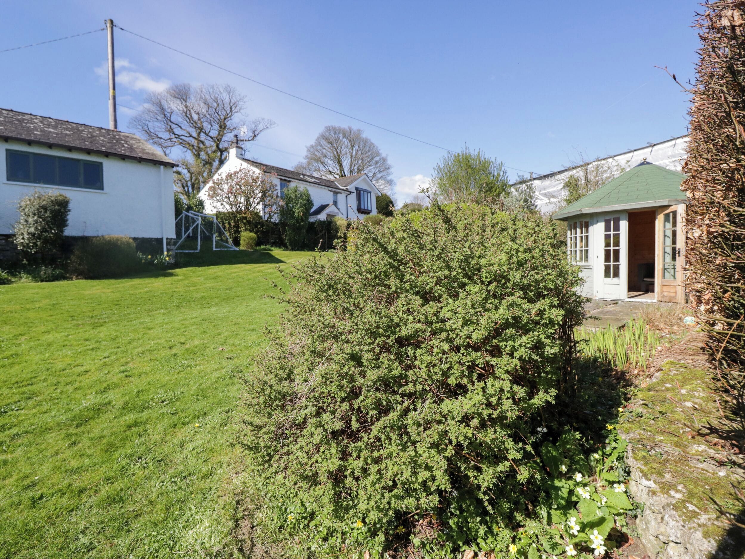 A residential area with a well-maintained lawn, a house with a green roof, and a small shed.