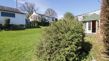 A residential area with a well-maintained lawn, a house with a green roof, and a small shed.