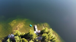 An aerial view of a lakeside property with a dock, a small boat, and a cabin surrounded by trees. - Tamar Vacations (Temagami)