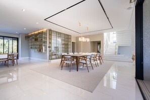 A spacious dining area with a large table and chairs, a built-in bookshelf, and a modern ceiling design. - Mansão de Luxo a 35 minutos de SP (Araçariguama)
