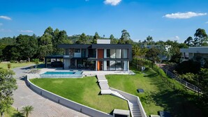A modern two-story house with a swimming pool, a covered patio, and a well-maintained lawn. - Mansão de Luxo a 35 minutos de SP (Araçariguama)