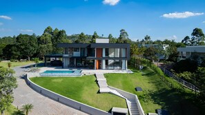 A modern two-story house with a swimming pool, a covered patio, and a well-maintained lawn. - Mansão de Luxo a 35 minutos de SP (Araçariguama)