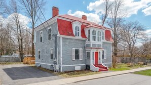 A two-story house with a red roof, white trim, and a front porch with steps.