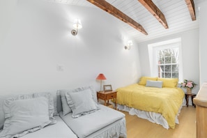 Une chambre à coucher avec un lit, un canapé, une table de chevet, une lampe et une fenêtre.