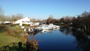 A calm river with boats docked, a white building, and leafless trees. - Welcome to your future cocoon! 54 m² house entirely renovated (Castelmoron-sur-Lot)