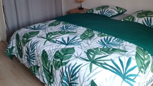 A bedroom with a bed, curtains, a nightstand, a lamp, and a wall decoration. - Welcome to your future cocoon! 54 m² house entirely renovated (Castelmoron-sur-Lot)