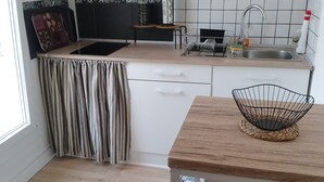 A kitchen with a striped curtain, a woven basket, and a tiled backsplash. - Welcome to your future cocoon! 54 m² house entirely renovated (Castelmoron-sur-Lot)