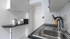 Eine moderne Küche mit Spüle aus Edelstahl, weißen Schränken, einer schwarzen Arbeitsplatte und einer Marmor-Spritzschutzwand.