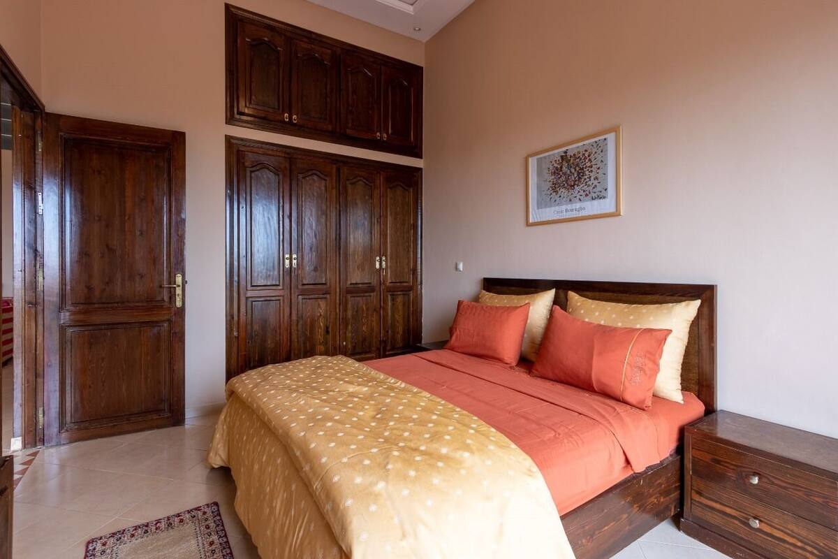 A bedroom with a bed, wooden wardrobe, and a framed picture on the wall.