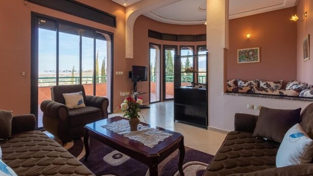 A spacious living room with a large window, a sofa, a coffee table, and a TV. - Le joyau de l'ourika (Ourika)