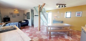 Ein Zimmer mit einer hölzernen Bank, einer Treppe, einem Esstisch und einem Fernseher.