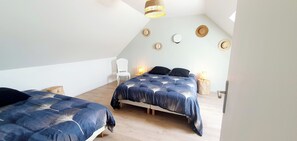 Ein Schlafzimmer mit zwei Betten, Holzboden und schrägen Decken.