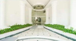 A corridor with white walls, green plants, and a tiled floor. - Acapulco Costera, Zona Dorada 300 m from the sea 🏖️🌊 (ACAPULCO DE JUÁREZ)
