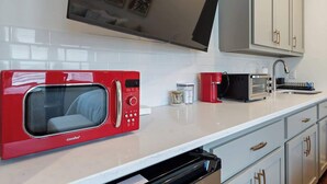Uma cozinha moderna com um micro-ondas vermelho, uma cafeteira e uma torradeira na bancada.