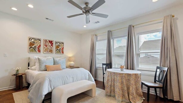 Um quarto com cama, um banco, uma mesa redonda com cadeiras e obras de arte na parede.