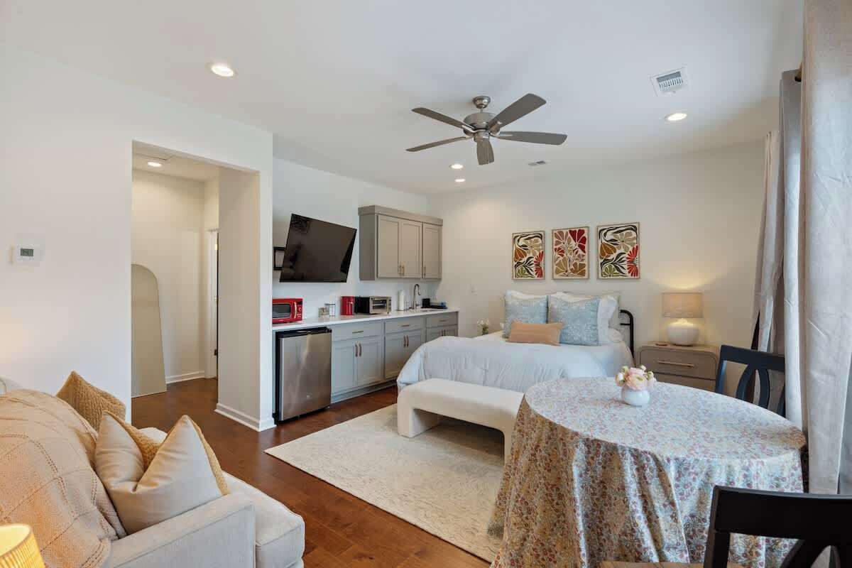 A bedroom with a bed, bedside table, and a small round table with a floral tablecloth.
