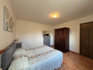 Un dormitorio con cama, cómoda, armario y una lámpara en el techo.