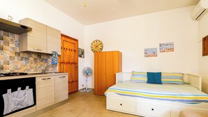 A compact bedroom with a bed, bedside table, and a small bedside fan. - Casetta sulla spiaggia by Casa di Marco (Padula Bianca)