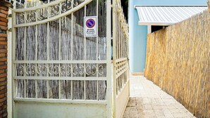 Un stretto vicolo con un cancello in metallo e una recinzione in bambù.