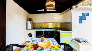 Una cucina compatta con lavatrice, lavello e zona pranzo con tavolo apparecchiato per due.