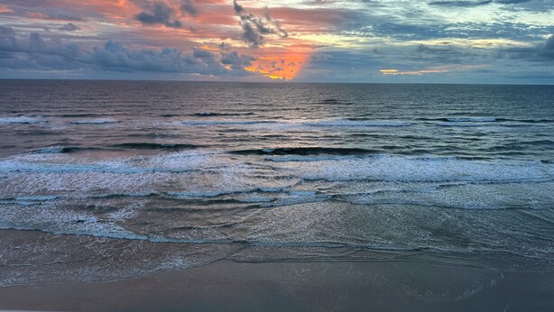 Una playa con olas y un atardecer.