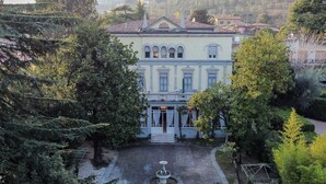 Un edificio grande con un patio central, una fuente y una fachada simétrica con ventanales en arco.