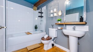 A bathroom with a bathtub, toilet, and sink. - Stylish 1BDR Duplex Loft Piccadilly (Manchester)