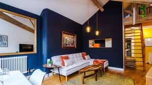 A modern living room with a sofa, a coffee table, and a dining area with a table and chairs. - Stylish 1BDR Duplex Loft Piccadilly (Manchester)
