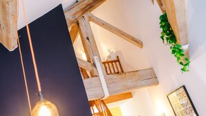 Ein Zimmer mit freiliegenden Holzbalken, einer hängenden Leuchte und einem gerahmten Wandplakat mit dem Alphabet.