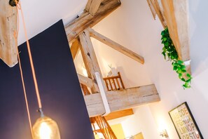 A room with exposed wooden beams, a hanging light fixture, and a framed alphabet poster on the wall. - Stylish 1BDR Duplex Loft Piccadilly (Manchester)