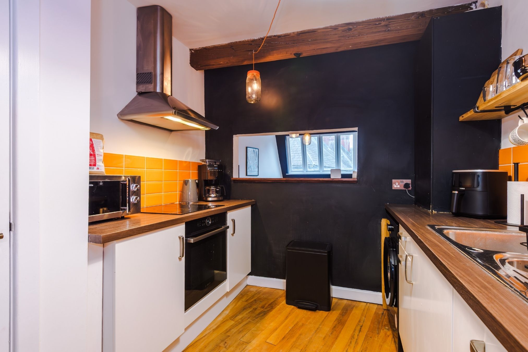 A compact kitchen with a built-in oven, a coffee machine, and a toaster.