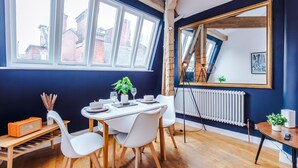 A dining area with a table set for two, a radiator, and a large mirror on the wall. - Stylish 1BDR Duplex Loft Piccadilly (Manchester)