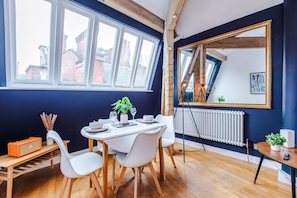 Ein Essbereich mit einem Tisch für zwei Personen, einem Heizkörper und einem großen Spiegel an der Wand.