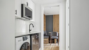 Una cocina compacta equipada con lavadora, microondas y horno empotrado.