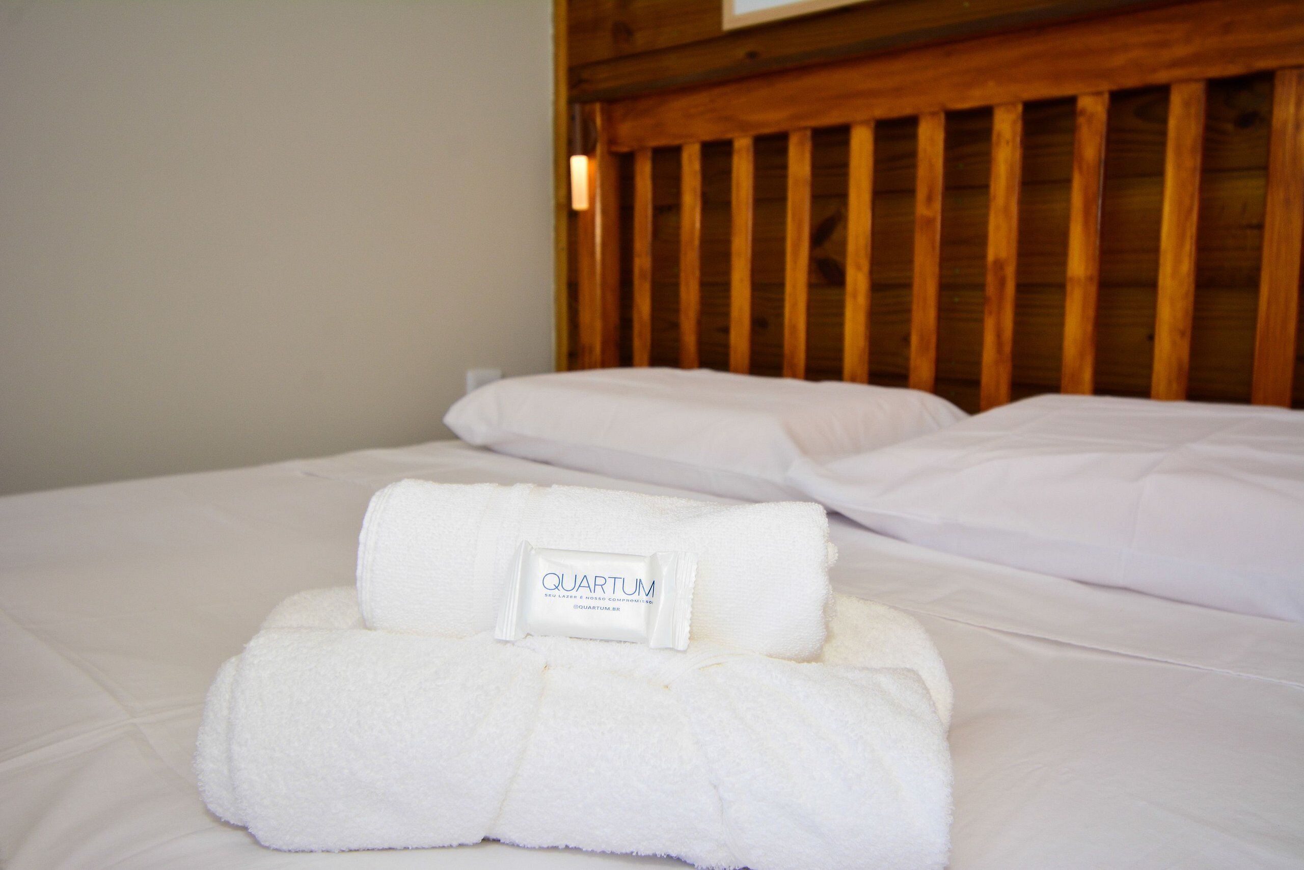 A bed with white linens and a folded towel with a label.