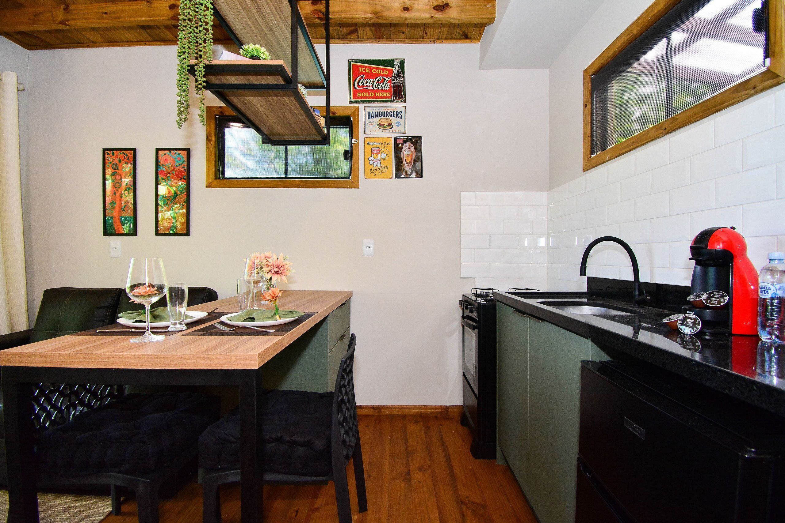 Une cuisine avec une table en bois, des chaises, un évier et une fenêtre.
