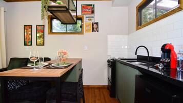 Une cuisine avec une table en bois, des chaises, un évier et une fenêtre.