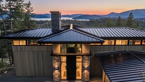 A modern house with a stone facade, large windows, and a metal roof. - The Edge - Modern Retreat with Panoramic Views (Sandpoint)