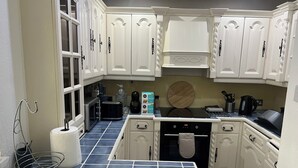 A kitchen with white cabinetry, a black stove, and a blue tiled floor. - Bright 2-Bed Apt with Balcony in Zone 2 London, 3min walk from MaidaVale tubestn (London)
