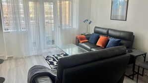 A living room with a black leather sofa, a glass coffee table, and a black armchair. - Bright 2-Bed Apt with Balcony in Zone 2 London, 3min walk from MaidaVale tubestn (London)