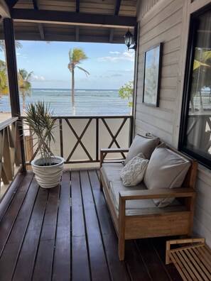 A wooden deck with a sofa and a potted plant, overlooking the ocean. - Alamar - Hotel Boutique  (Mahahual)