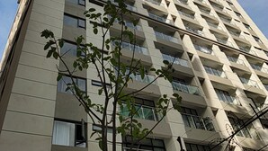 A tall, multi-story building with a modern architectural design, featuring a series of balconies and windows. - Charming 1-bedroom apartment in vibrant Nairobi with fitness room (Nairobi)