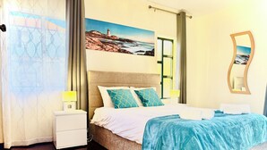 Quarto com cama, mesas de cabeceira, um quadro, um espelho e janela com cortinas.