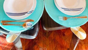 Mesa posta com pratos, talheres e uma cesta de frutas.
