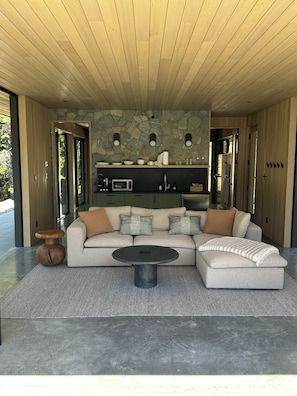 Una sala de estar moderna con un sofá modular, una mesa de centro redonda y una pared de acento de piedra.