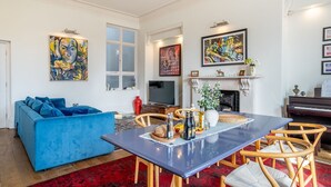 A living room with a blue sofa, wooden chairs, a dining table, and artwork on the walls. - The Classic on the Mount -  a premium stay that sleeps 4 guests  in 2 bedrooms (York)