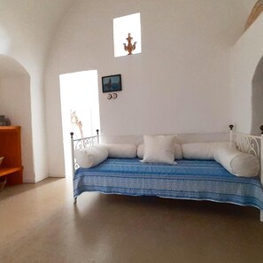 Una habitación con una cama, un estante pequeño y un cuadro en la pared.