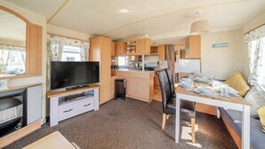 A compact RV kitchen with a TV, dining table, and seating area. - Cayton Bay Caravan for 6, Pet Friendly & Parking (Scarborough)
